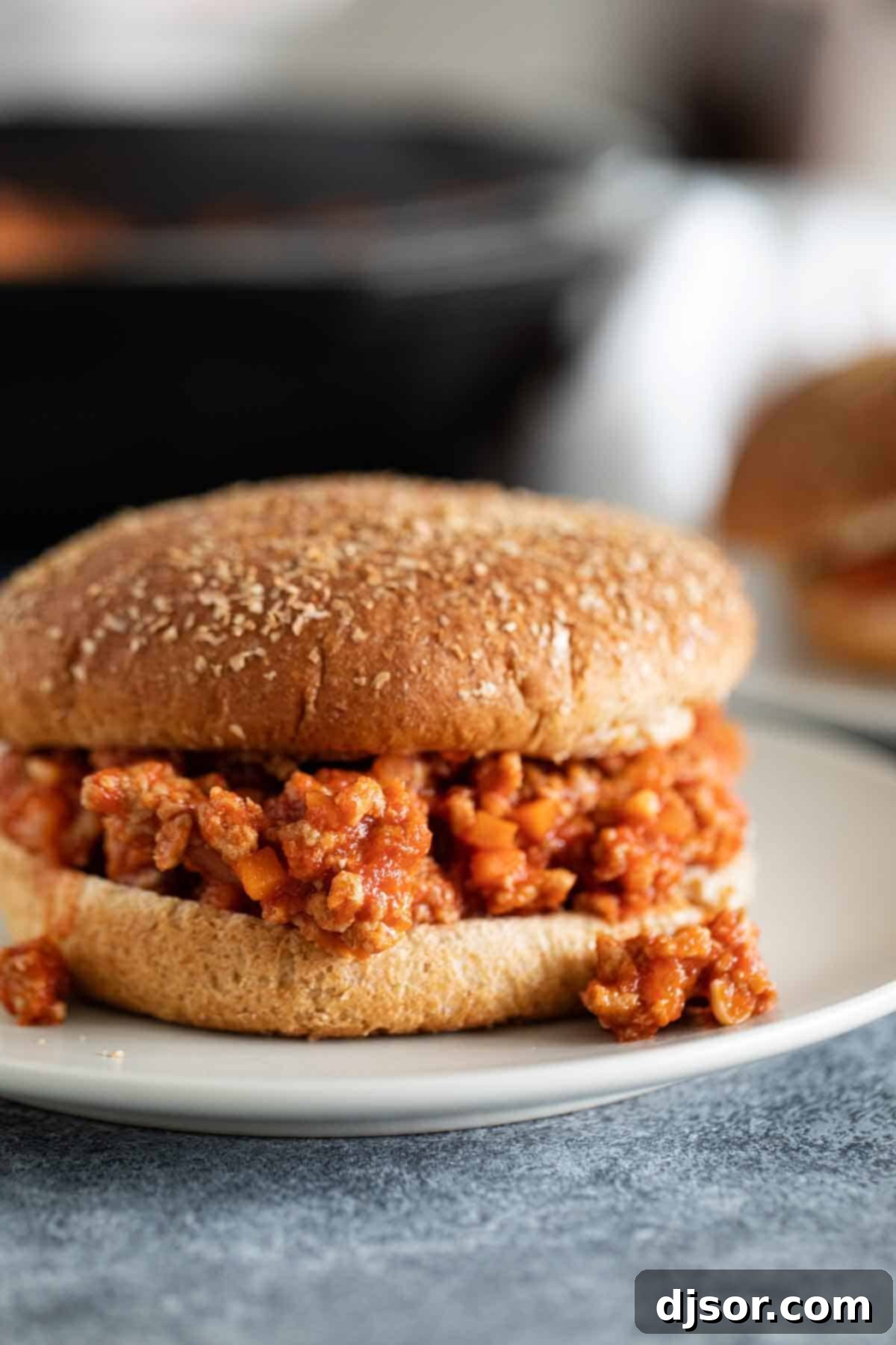 Perfectly Piled Healthy Turkey Sloppy Joe on a Whole Wheat Bun A close-up shot of a healthy turkey sloppy joe, piled high on a toasted whole wheat bun, garnished with a sprinkle of fresh parsley, showcasing its juicy and flavorful filling.
