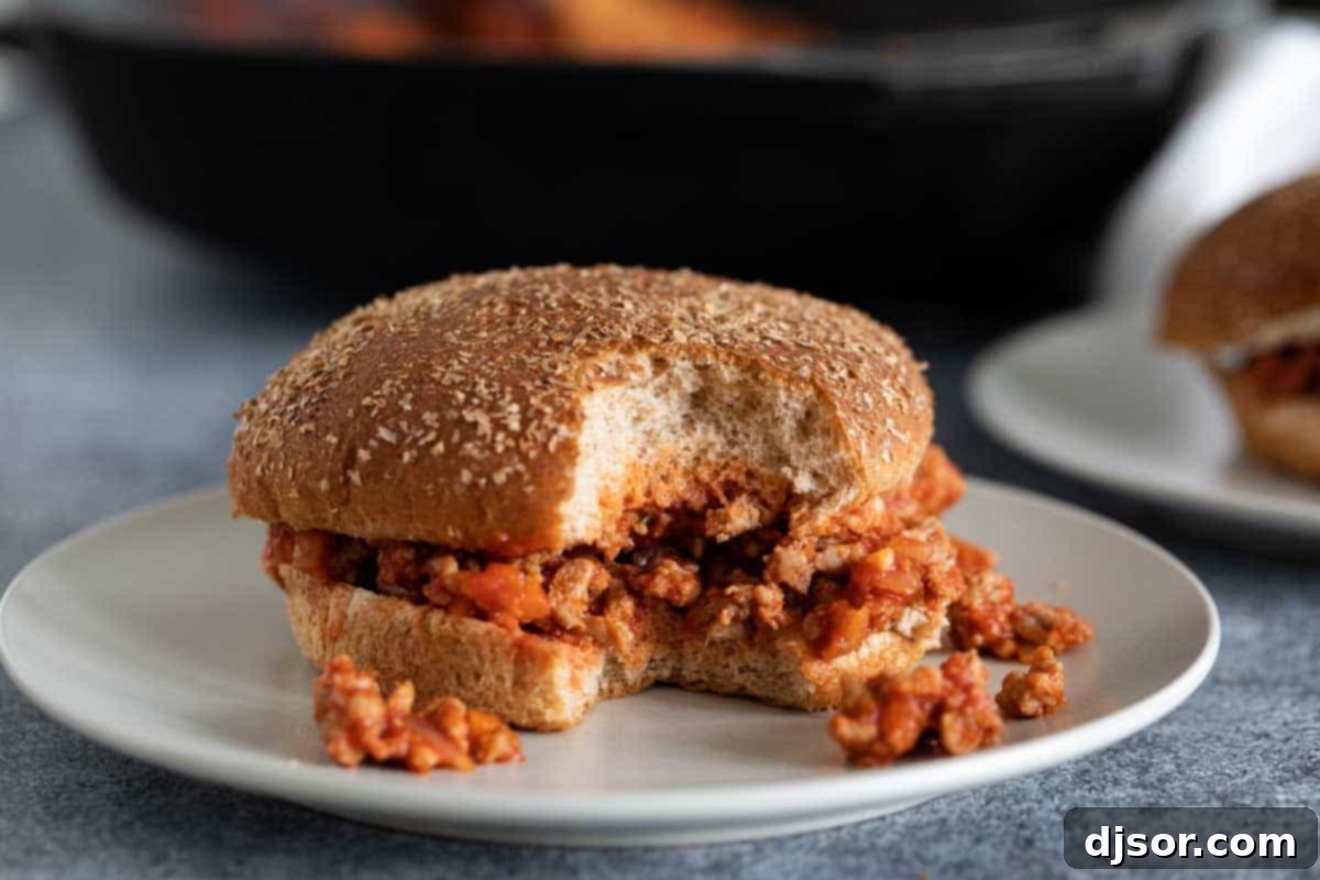 Enjoying a Healthier Turkey Sloppy Joe: A Delicious Bite A turkey sloppy joe on a plate with a bite taken out, showing the rich, saucy filling and toasted whole wheat bun, ready for a delicious healthy meal.