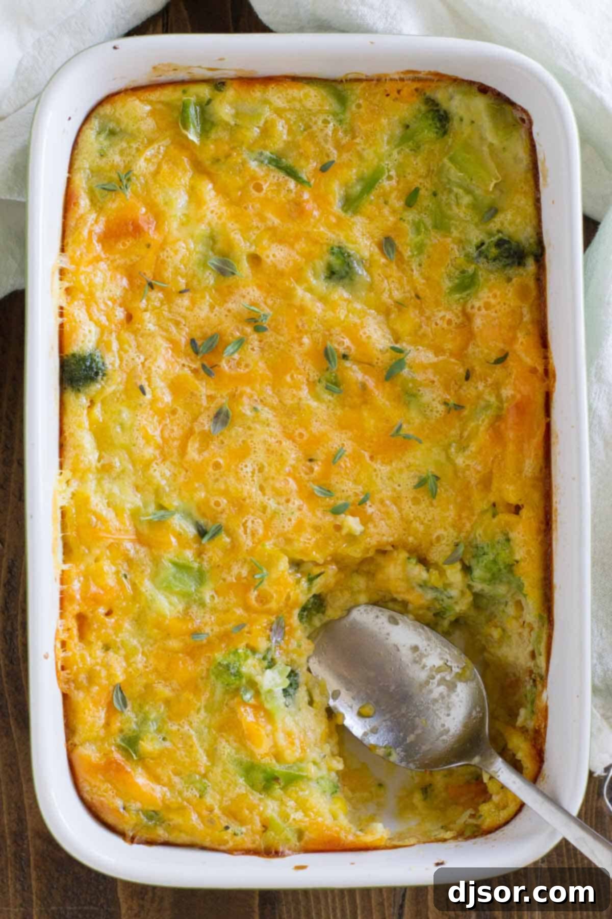 A delicious side dish, corn and broccoli are baked with cheese until bubbly and hot. This Scalloped Corn and Broccoli makes a comforting side dish that everyone will beg for. An inviting overhead view of the Scalloped Corn and Broccoli casserole, showcasing its golden-brown crust, visible bits of green broccoli, and the creamy, cheesy texture beneath, ready to be enjoyed.