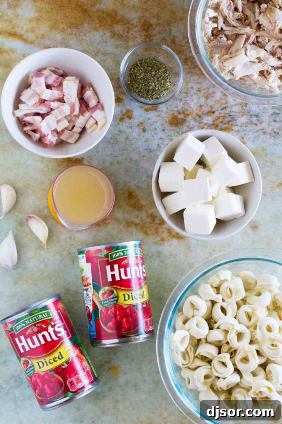 Essential ingredients laid out for preparing a quick and flavorful Creamy Tomato Tortellini with Chicken and Bacon, including canned tomatoes, frozen tortellini, crispy bacon, and cooked chicken.
