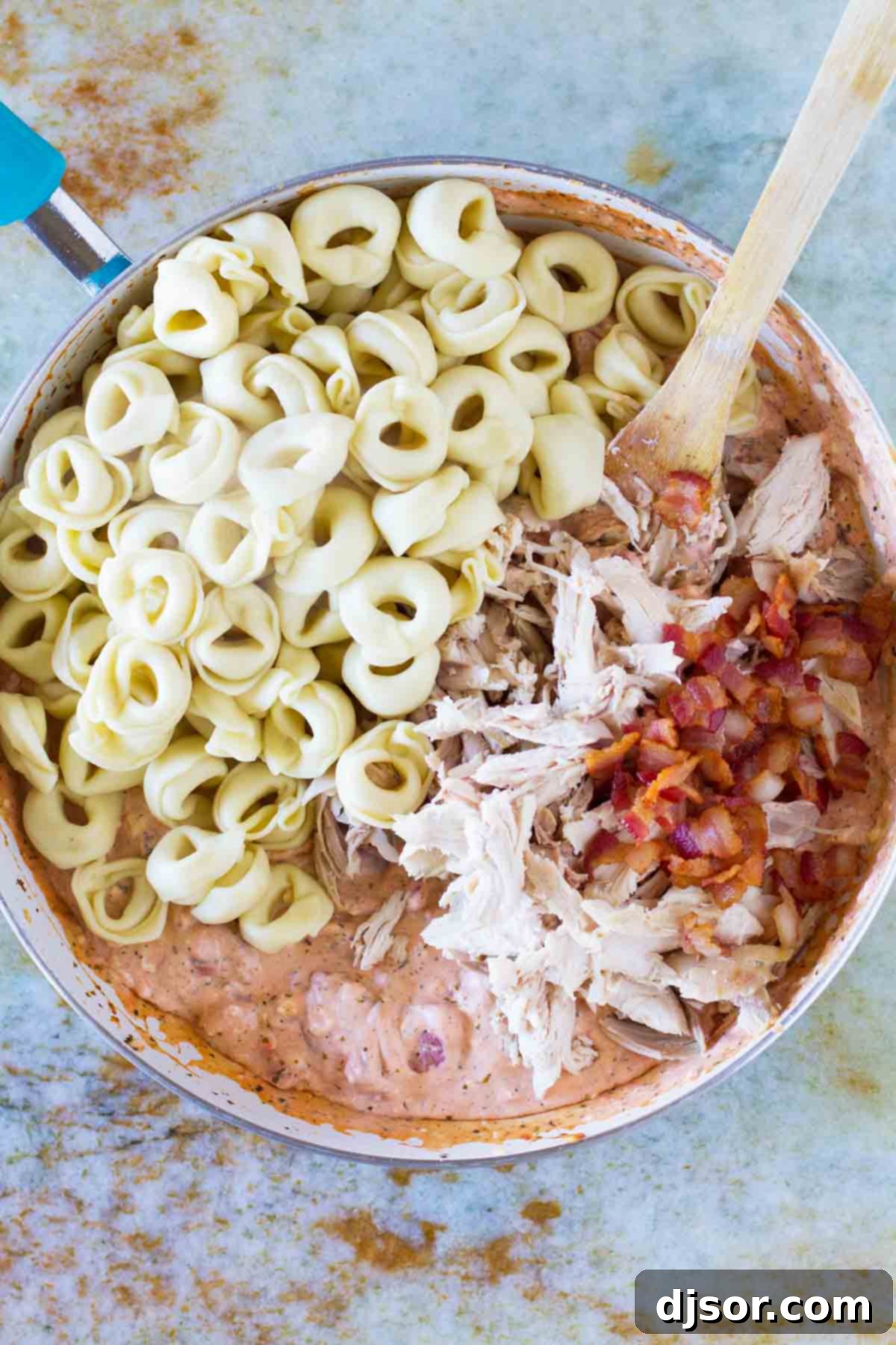 The process of combining various ingredients, including a rich sauce, perfectly cooked tortellini, tender chicken, and crispy bacon, in a large skillet to create a cohesive and flavorful weeknight dish.