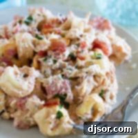 Serving of Creamy Tomato Tortellini with Chicken and Bacon on a plate with a fork.