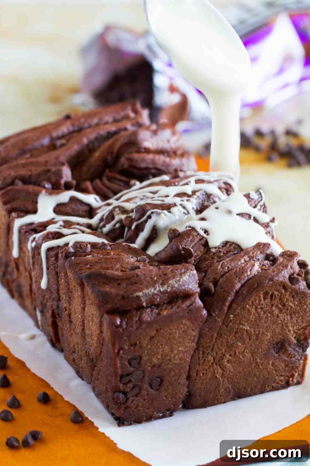 Decadent Chocolate Pull-Apart Loaf 4 Someone drizzling white cream cheese icing over a freshly baked chocolate pull apart bread