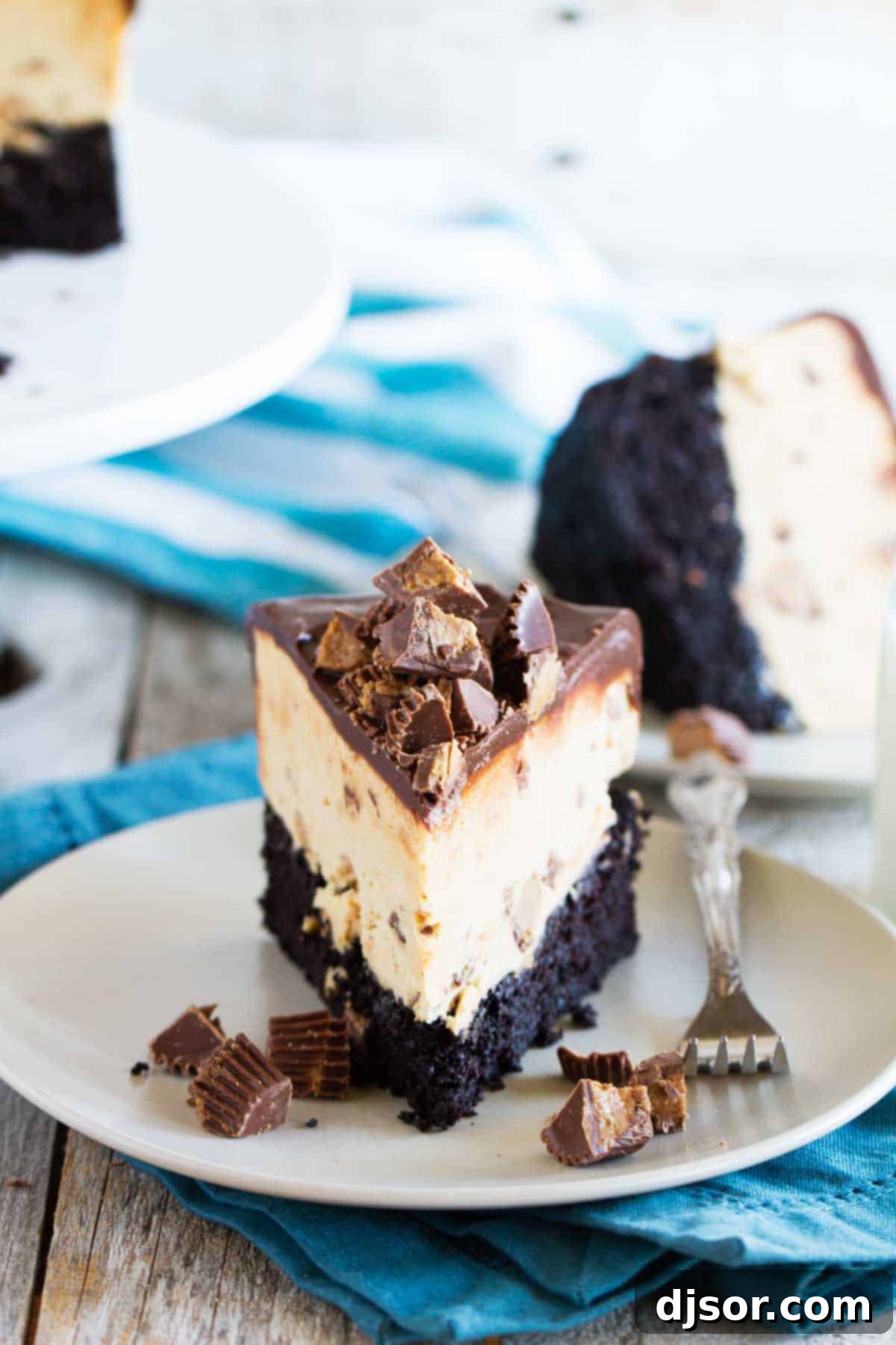 Ultimate Peanut Butter Cup Ice Cream Cake 4 Slice of peanut butter ice cream cup on a plate with chunks of peanut butter cups on top and on the sides.