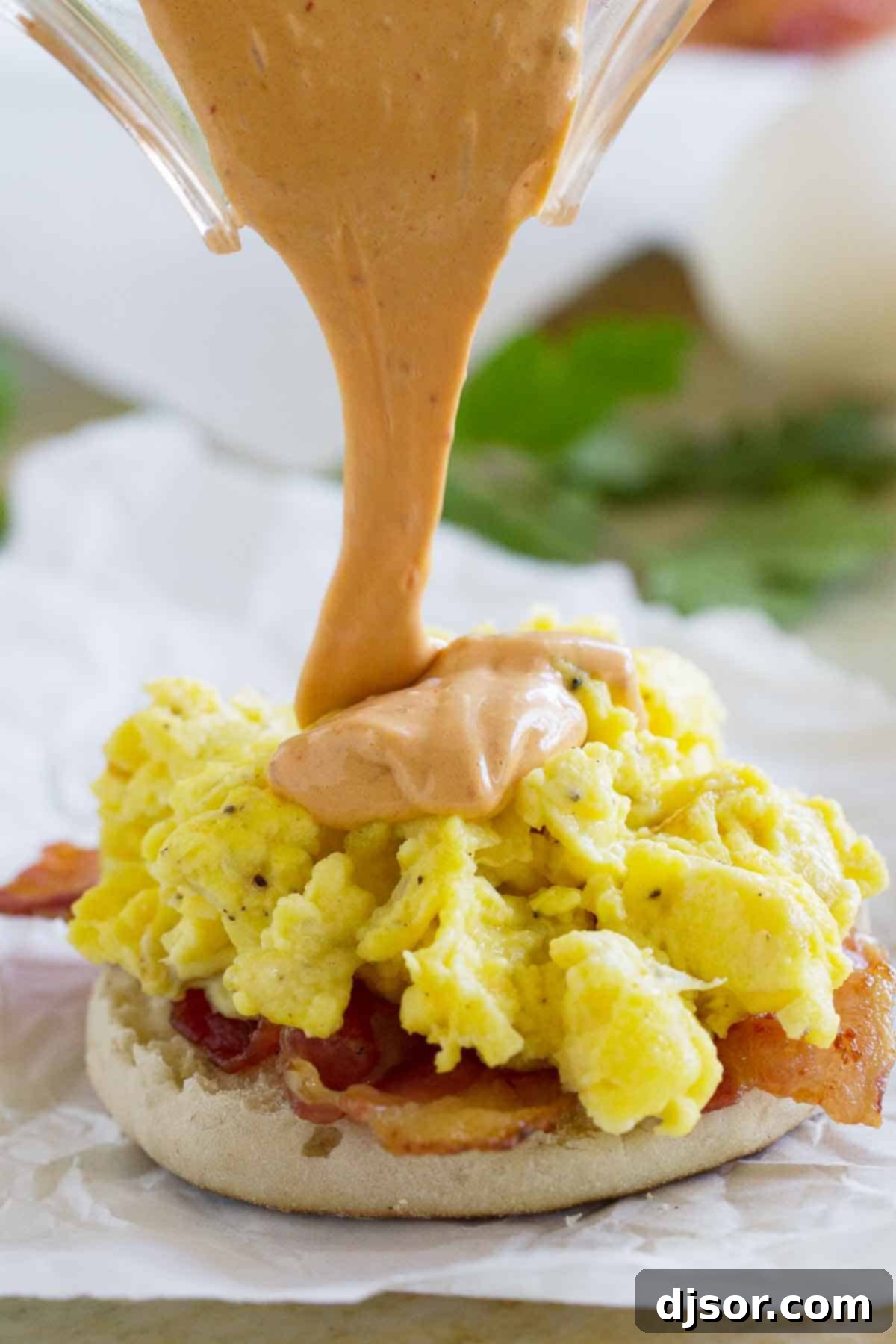 Pouring chipotle hollandaise sauce on top of egg sandwich