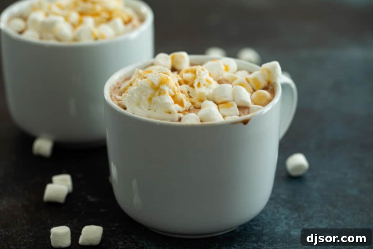 A large mug of creamy Salted Caramel Hot Chocolate, topped generously with fluffy whipped cream and a sprinkle of mini marshmallows, ready to be enjoyed on a cold day.