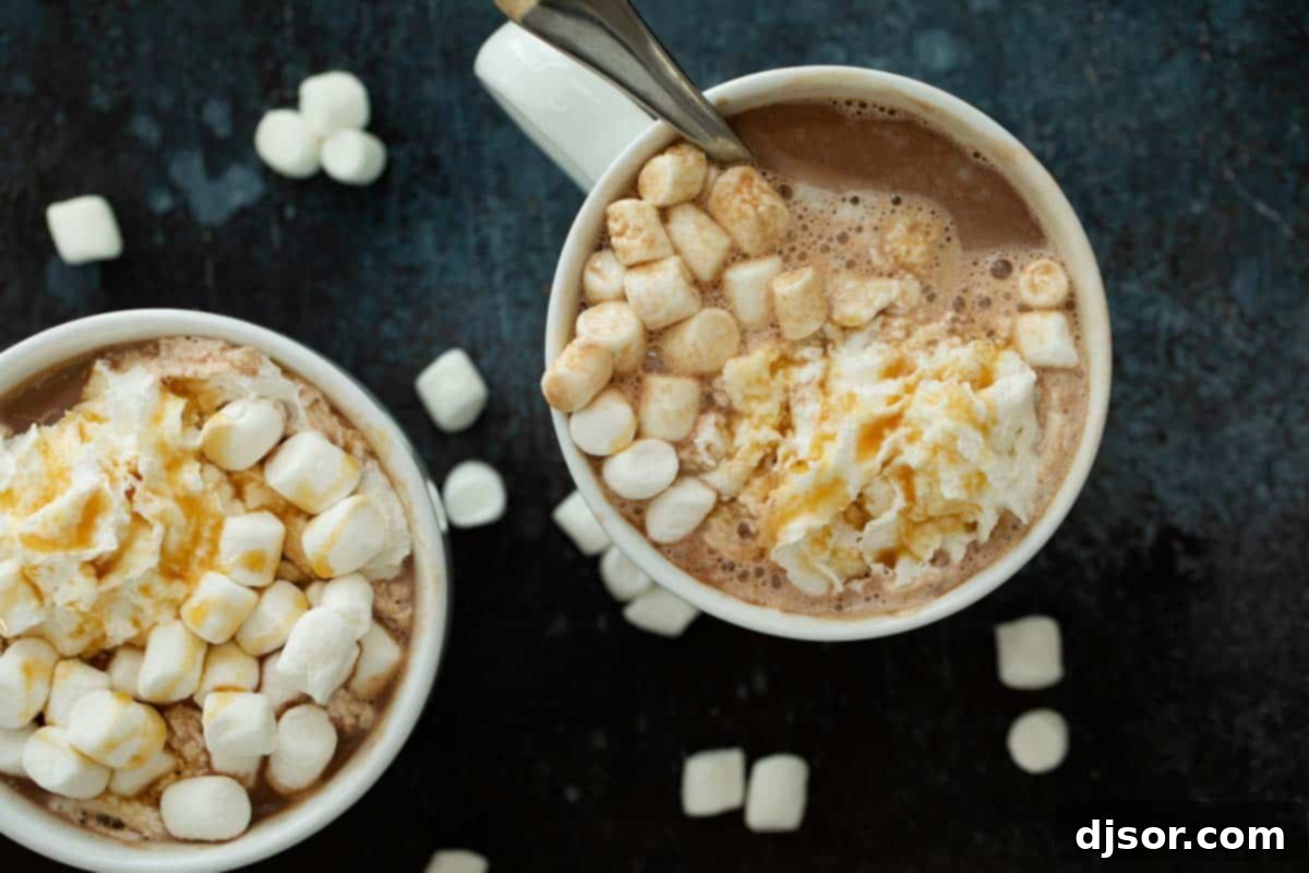 Three elegant mugs of Salted Caramel Hot Chocolate, one topped with whipped cream, others with a smooth, dark surface, showcasing the inviting richness of the beverage.