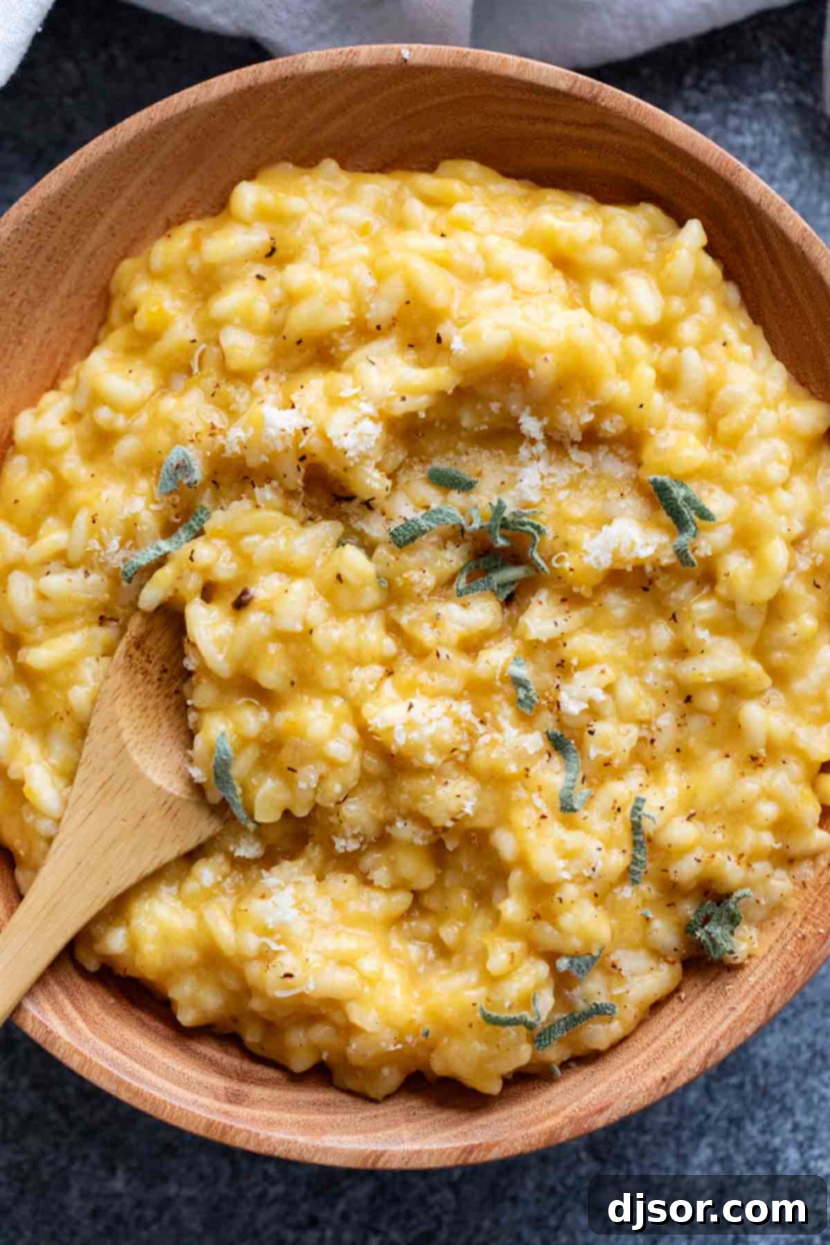 Golden Butternut Risotto 8 A wooden bowl of butternut squash risotto topped with fresh sage, ready to be enjoyed as a comforting meal.