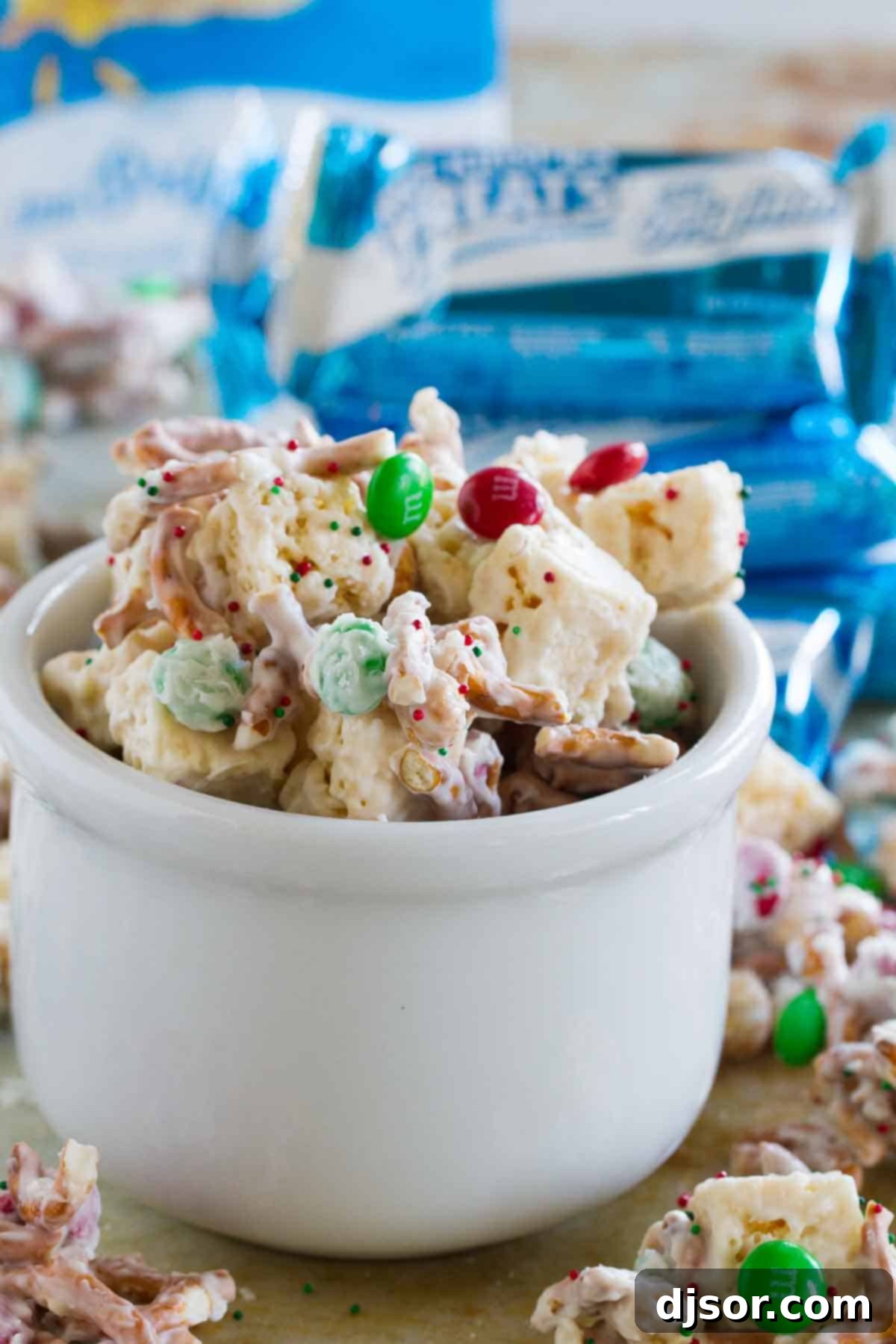 A large bowl overflows with Sweet and Salty Christmas Mix, showcasing the pretzels, candies, and Rice Krispies treats.