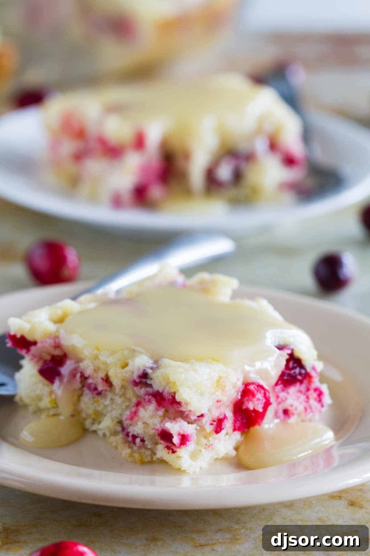 slice of cranberry cake with warm butter sauce on a plate with a fork
