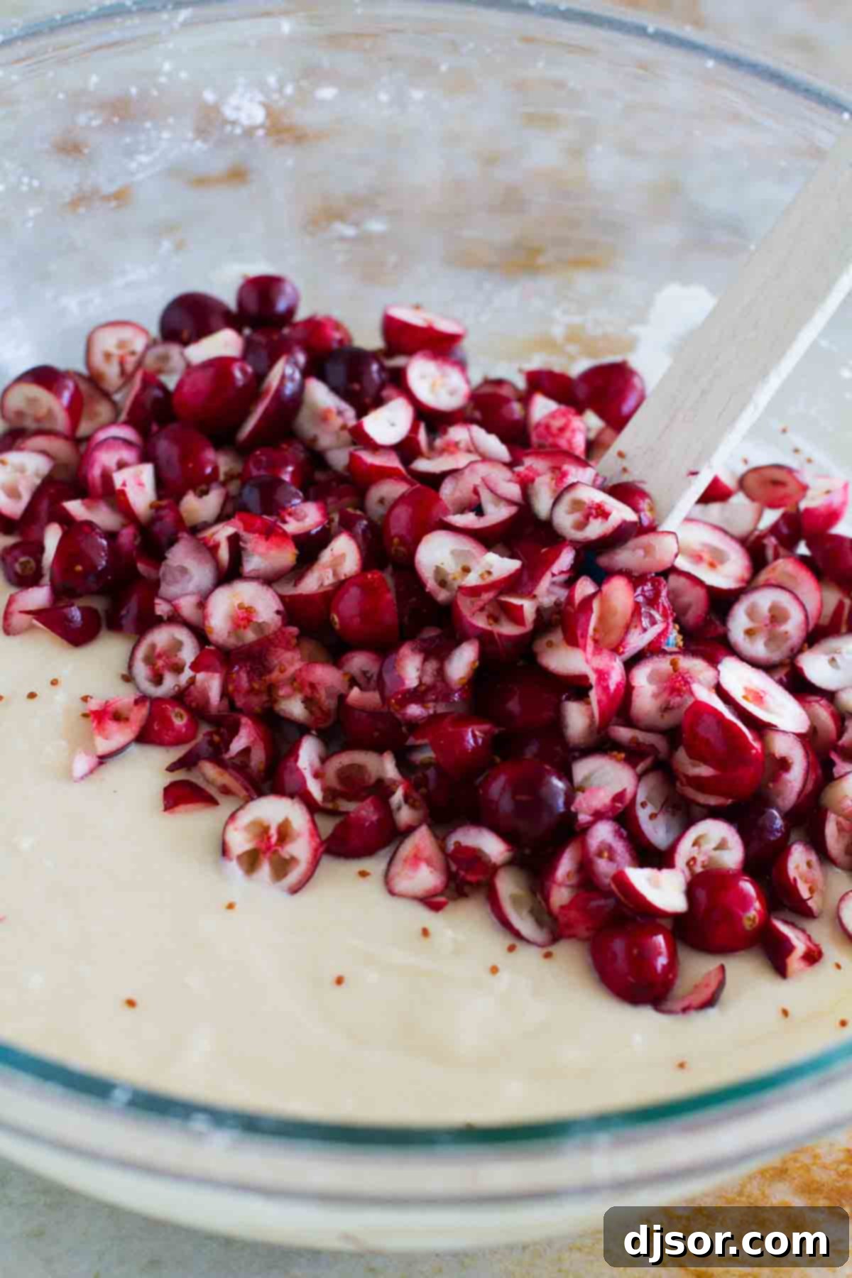 cake batter in a bowl with fresh, chopped cranberries