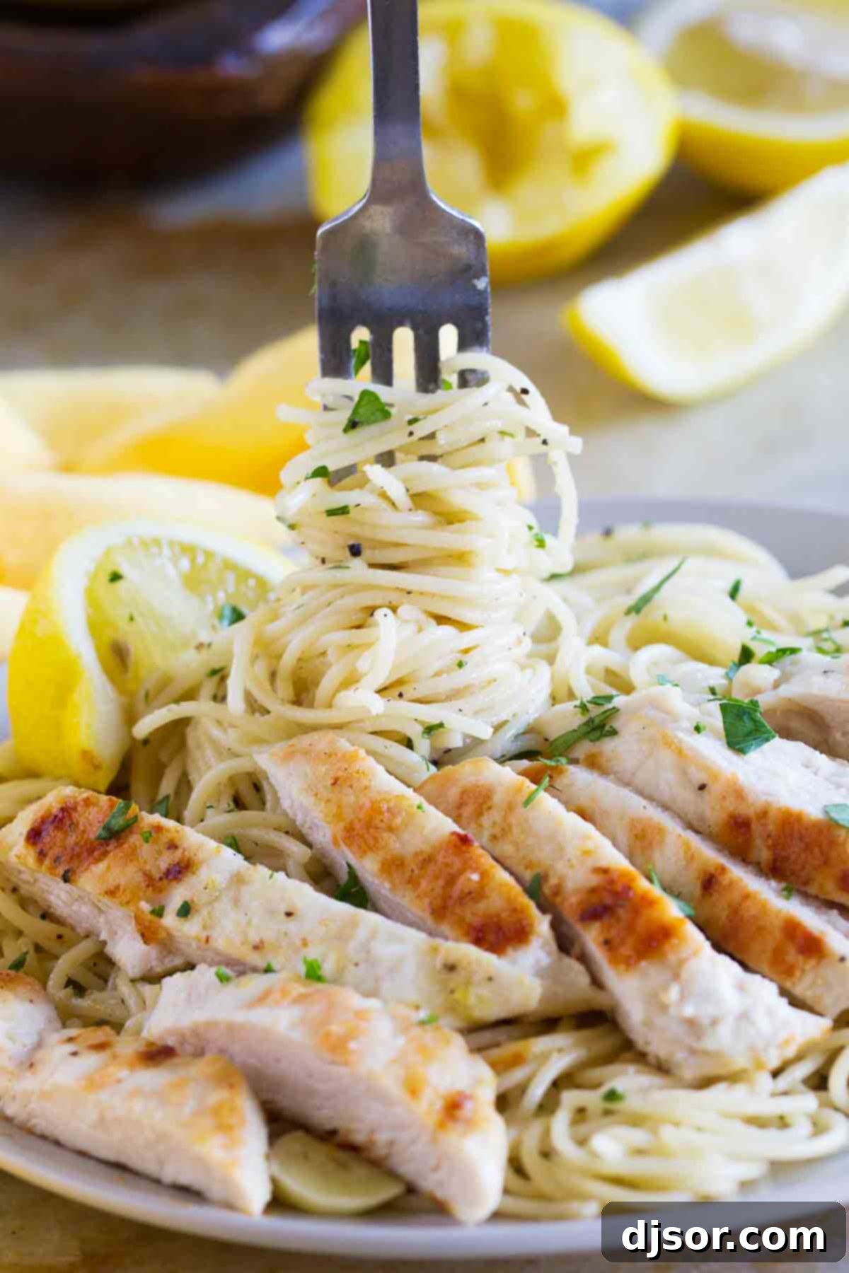 Fork with twirled pasta and a piece of lemon chicken