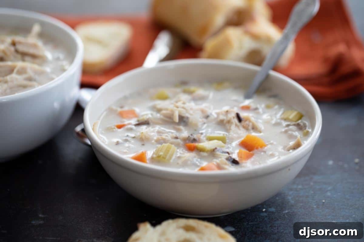 bowl of creamy chicken wild rice soup in a bowl with a spoon, garnished with fresh parsley