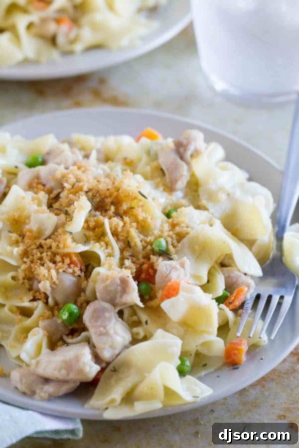 A full bowl of Chicken Pot Pie Ragu, garnished with fresh herbs and a spoon, ready to be enjoyed.