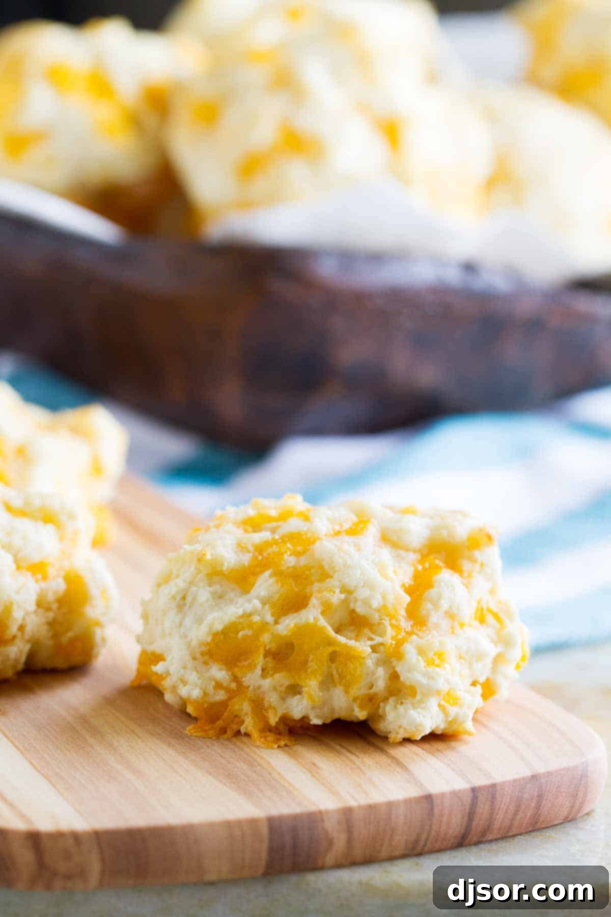 Golden-brown Garlic and Cheddar Sour Cream Biscuits arranged on a rustic cutting board