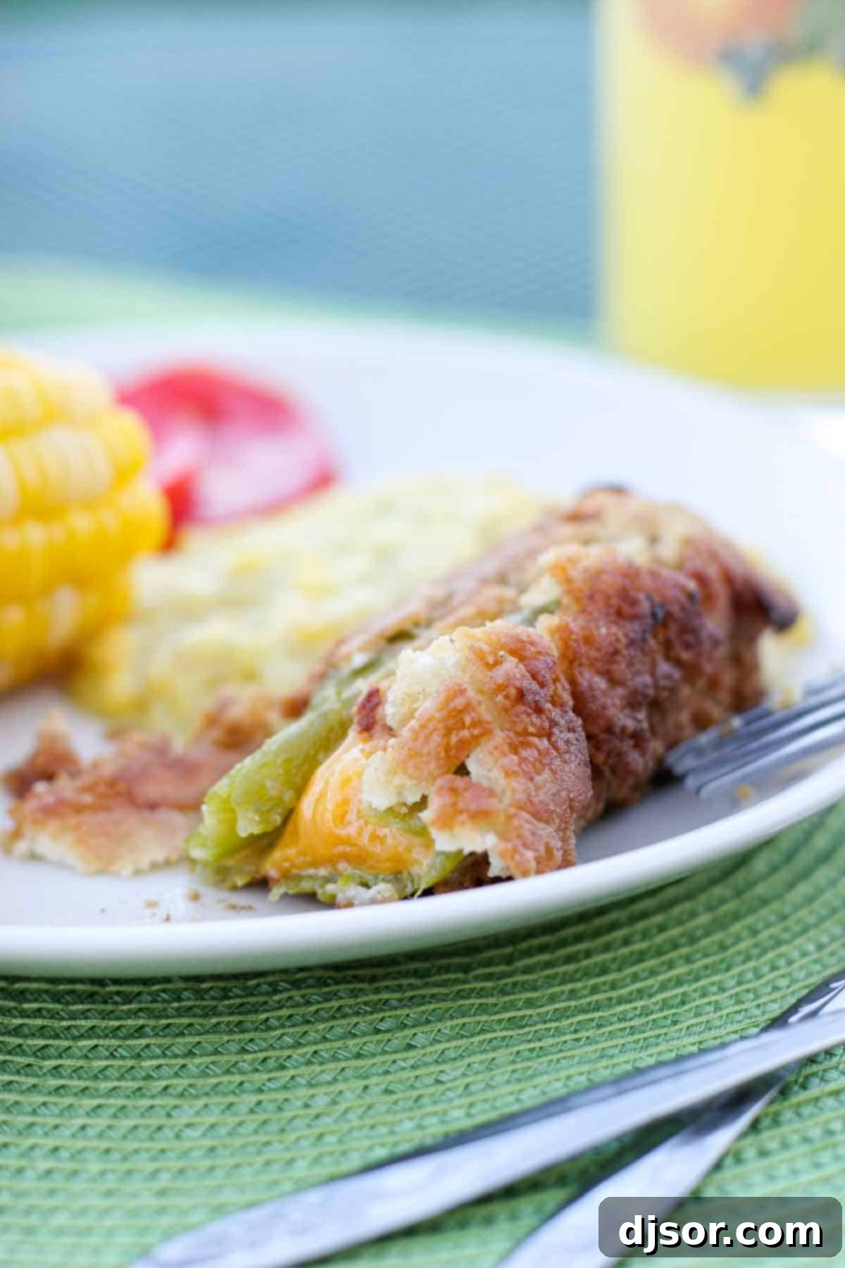 Homemade Chile Rellenos: A Taste of Home A close-up of a freshly fried chile relleno on a white plate, revealing a perfect bite taken out, showcasing the melted cheddar cheese oozing from its vibrant green chile center.
