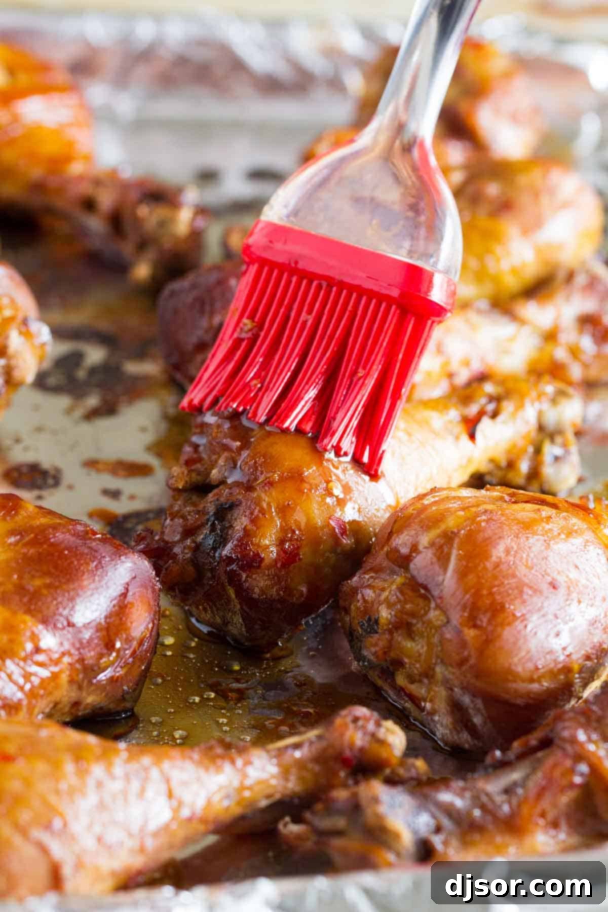 Practically dump and cook, these Slow Cooker Sweet Chili Chicken Drumsticks are full of Asian flavor and the slow cooker makes them easy as can be. A hand brushing sweet chili sauce onto tender chicken drumsticks, ready for the broiler.