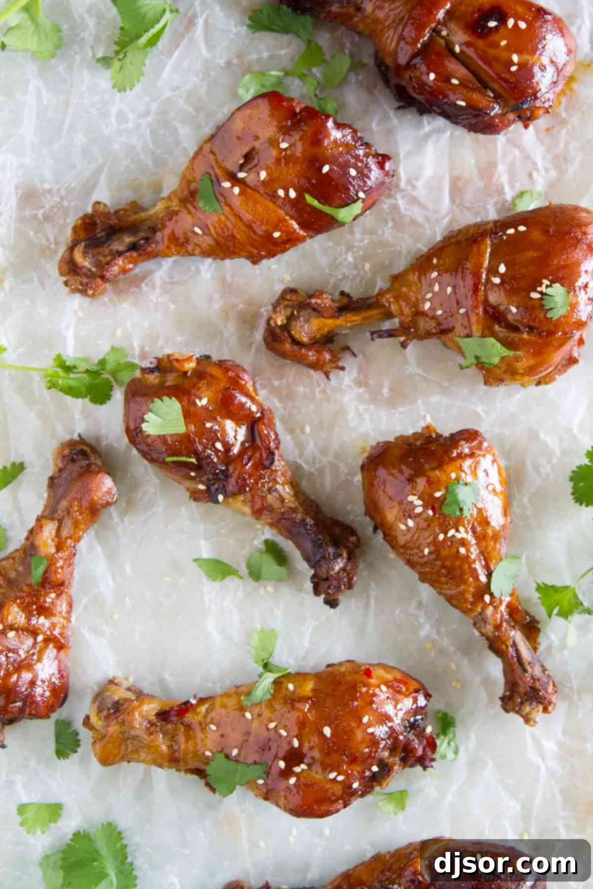 Practically dump and cook, these Slow Cooker Sweet Chili Chicken Drumsticks are full of Asian flavor and the slow cooker makes them easy as can be. Delicious Slow Cooker Sweet Chili Chicken Drumsticks served on parchment paper, highlighting their glossy sauce.