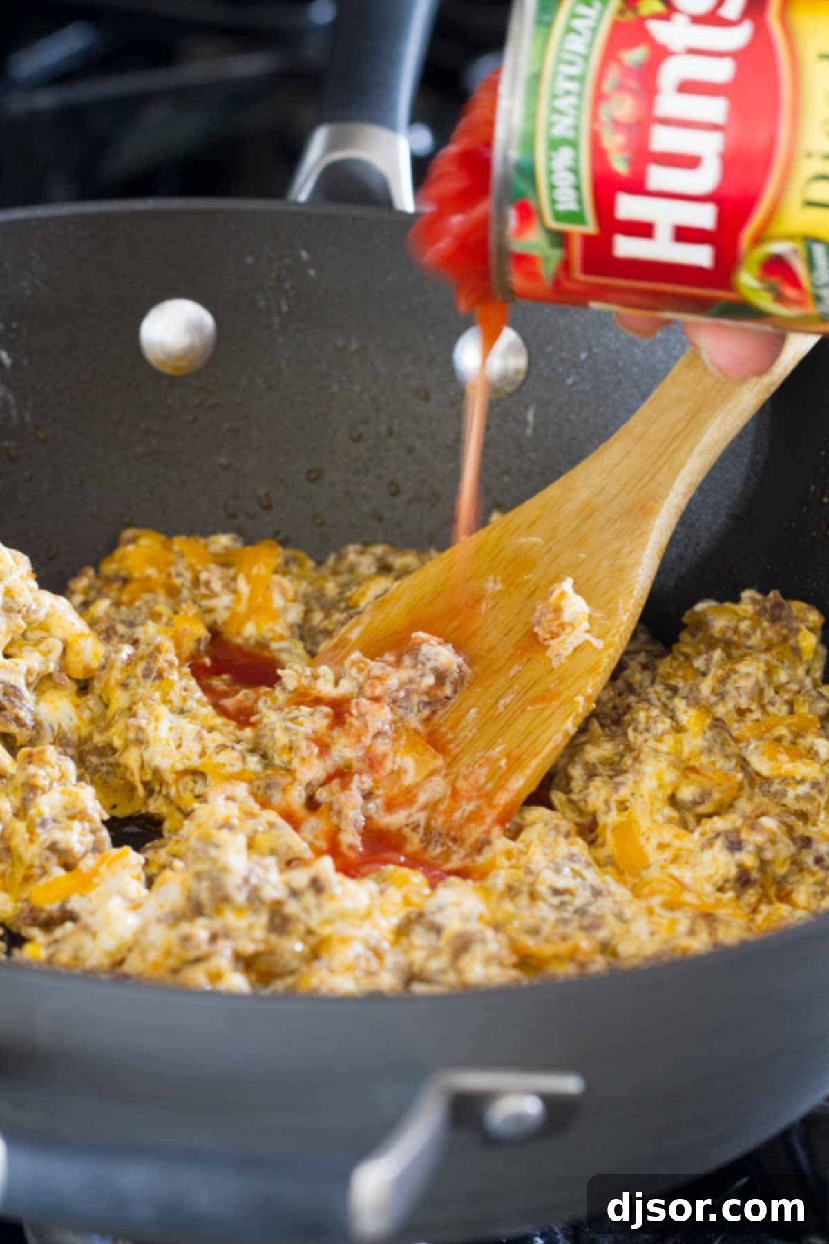 Kickin' Sausage Dip 3 Adding diced canned tomatoes into a skillet with the spicy sausage and cheese mixture.