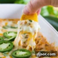 Kickin' Sausage Dip 6 Using a chip to get a cheesy bite of spicy sausage dip, showing cheese pull.