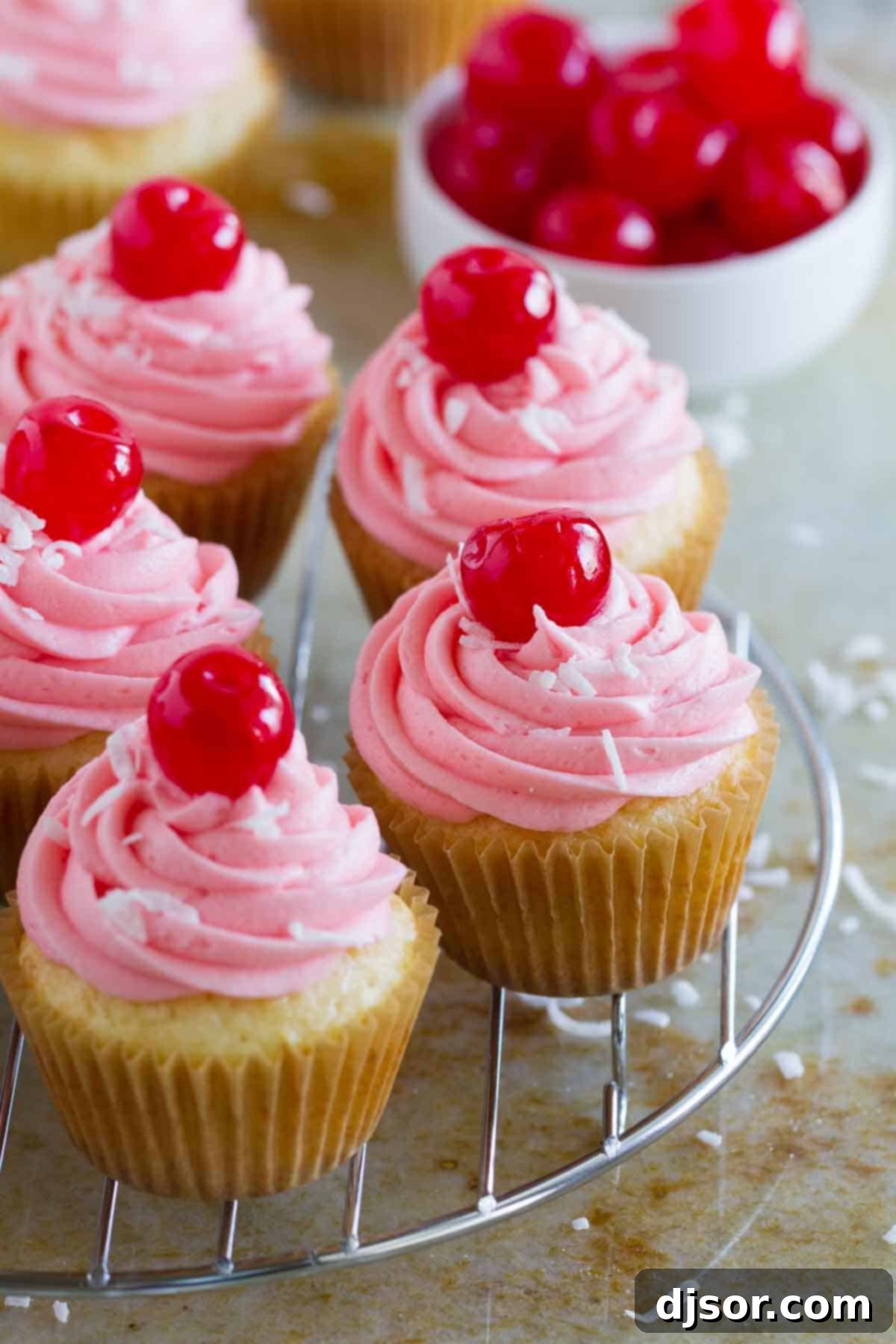 Freshly baked Coconut Cherry Cupcakes cooling on a wire rack, ready for frosting.