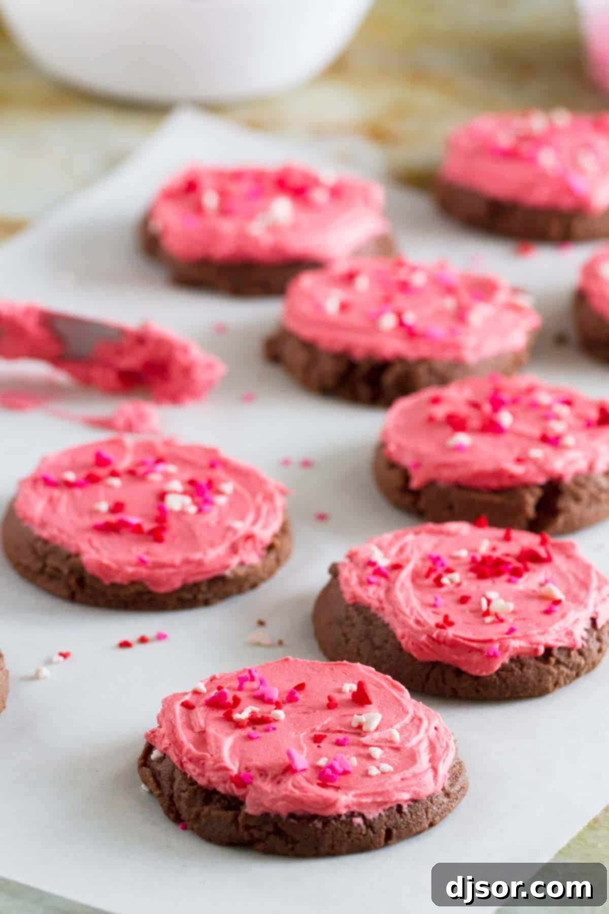 Batch of unfrosted chocolate sugar cookies cooling on a sheet of parchment paper, showcasing their deep brown color and soft texture before decoration.