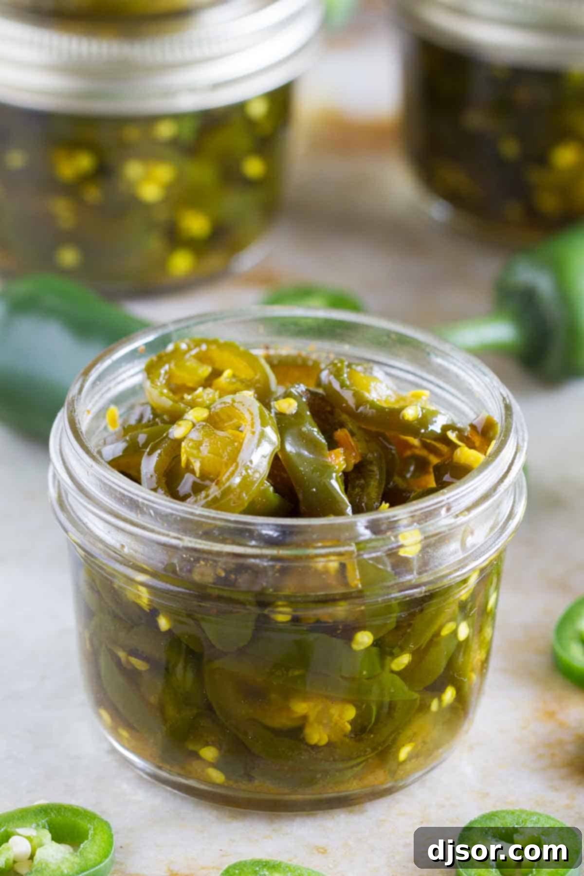 Candied Jalapeños in a jar, showcasing their glossy, vibrant appearance.