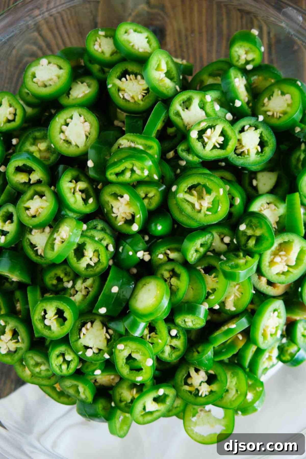Raw jalapeños, uniformly sliced and ready for preparation, resting in a bowl.
