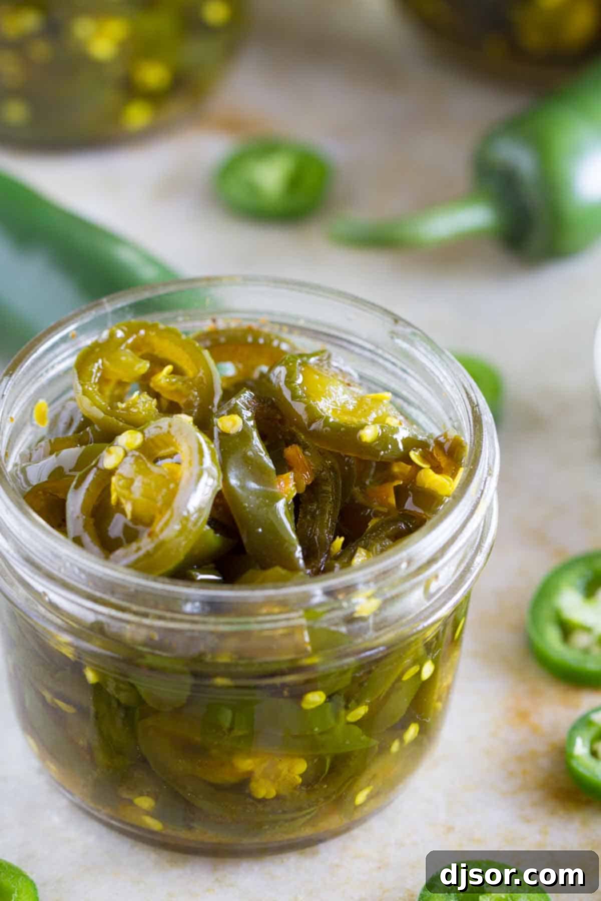 A small, beautifully sealed jar of homemade candied jalapeños, ready to be enjoyed.