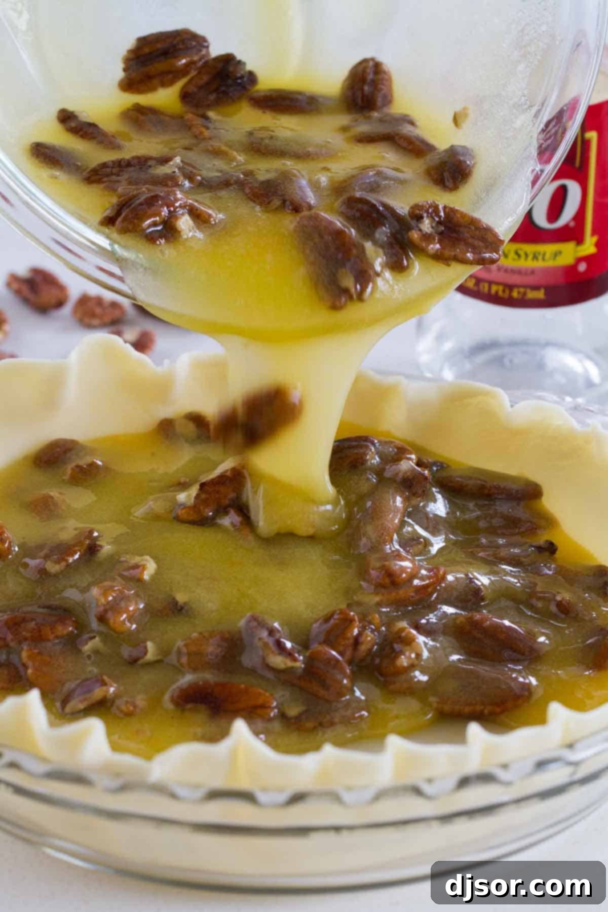 Viscous, golden pecan pie filling being carefully poured into an unbaked pie crust, showcasing the rich texture.