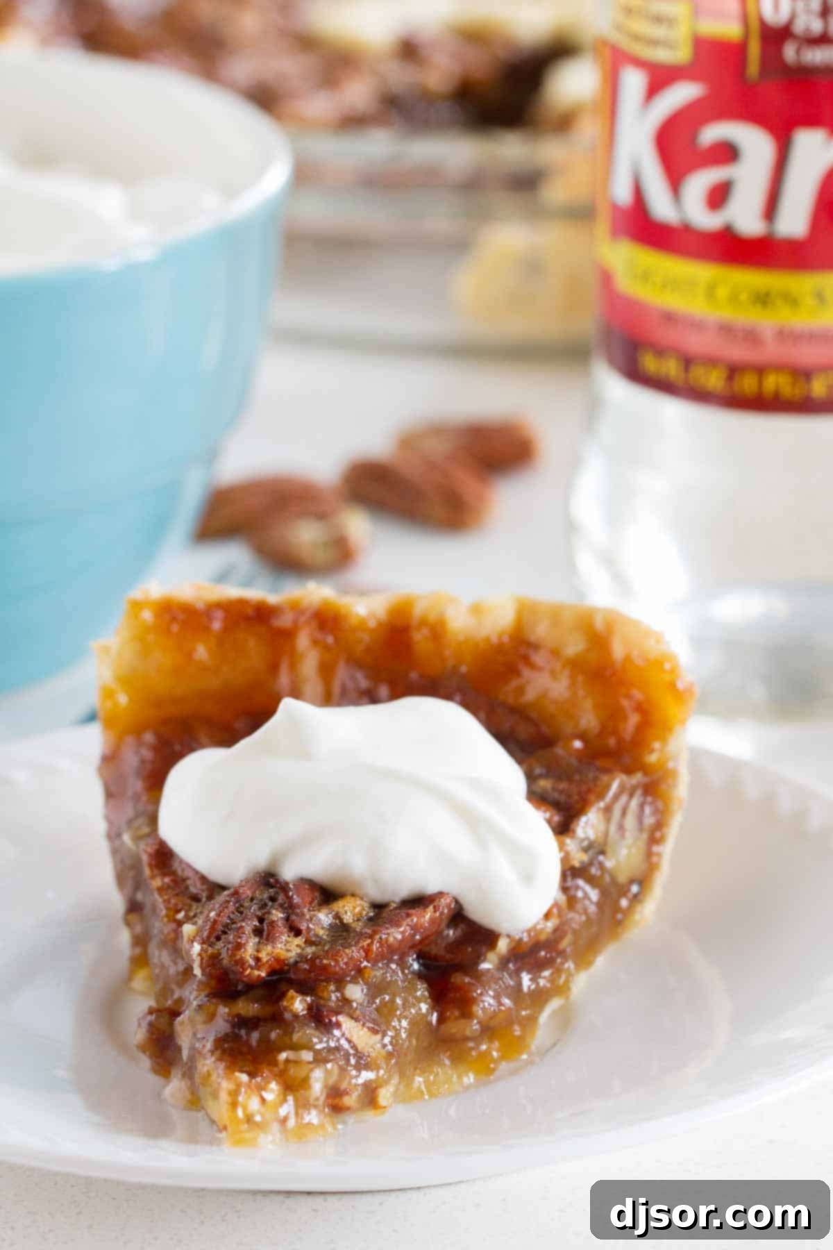 A perfect slice of Classic Pecan Pie, showcasing its rich, gooey filling and crunchy pecans, topped with a dollop of whipped cream.