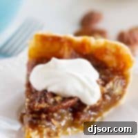 Slice of Classic Pecan Pie with a dollop of whipped cream on top, ready for serving.