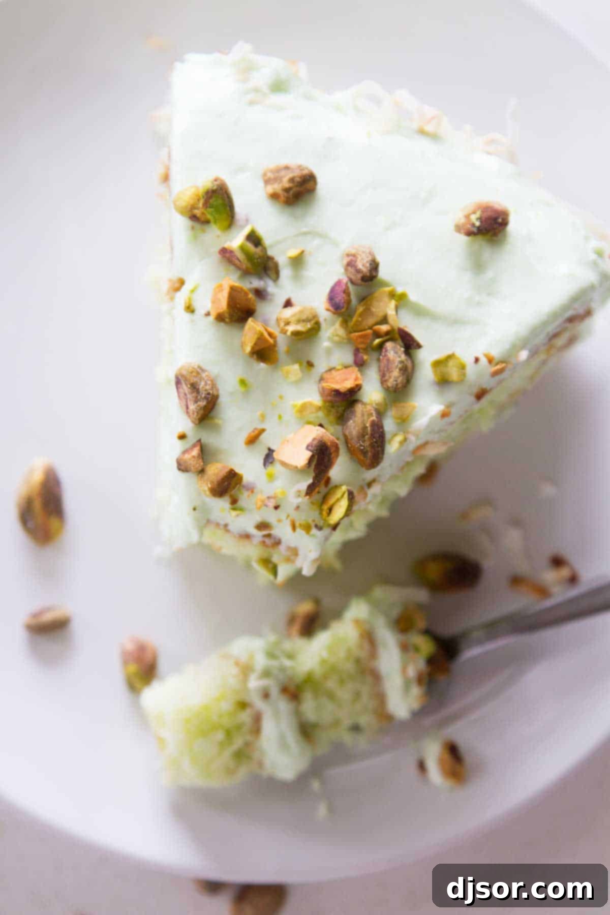 Slice of pistachio pudding cake with a forkful taken from the corner.