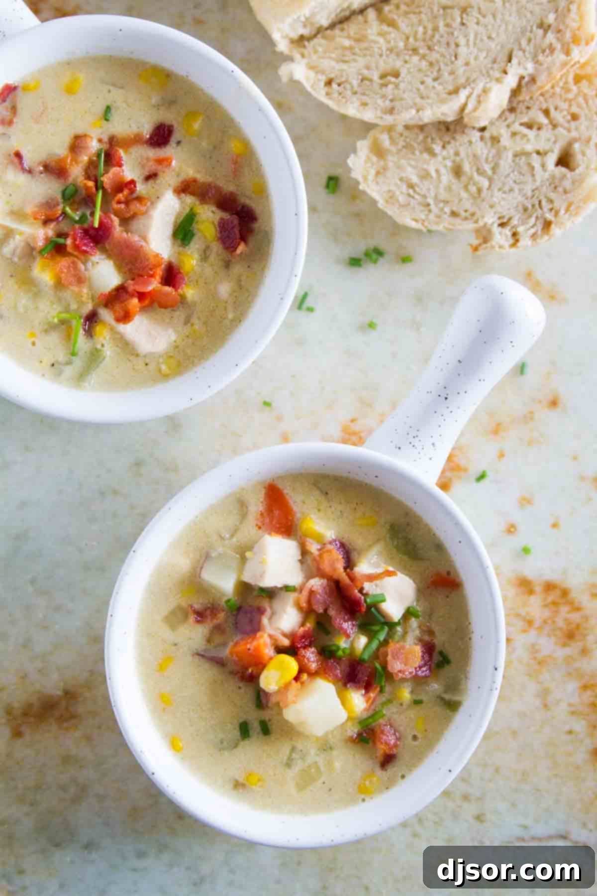 Garnished Chicken Corn Chowder A perfectly portioned bowl of New England Chicken Corn Chowder, topped generously with crispy bacon bits and finely chopped green chives, ready to be enjoyed.