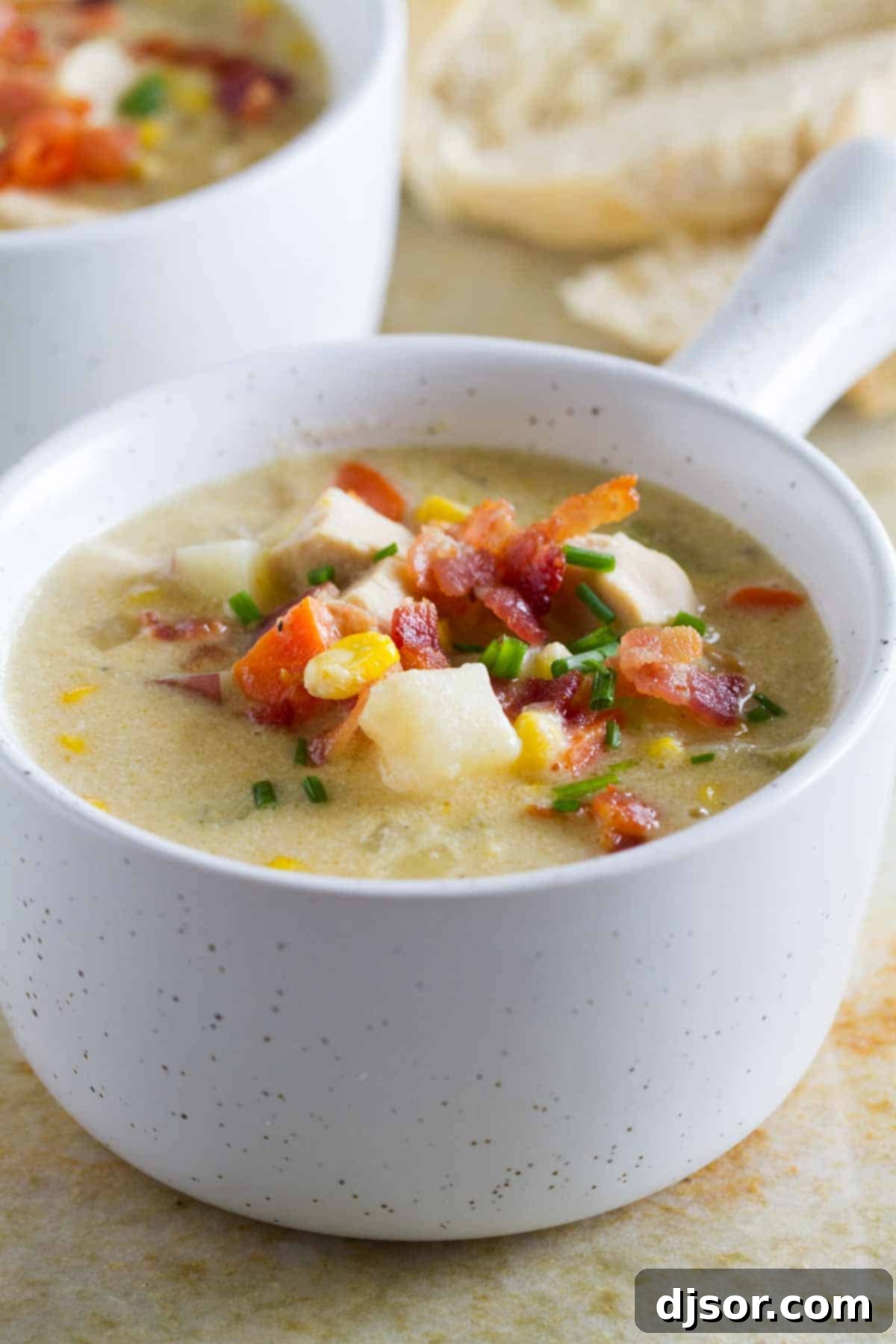 Hearty Bowl of Chicken Corn Chowder A close-up shot of a small bowl of creamy New England Chicken Corn Chowder, filled with hearty pieces of chicken, tender red potatoes, and vibrant corn kernels, ready to eat.
