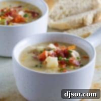 Comforting New England Chicken Corn Chowder 2 Two bowls of New England Chicken Corn Chowder, garnished with bacon and chives.