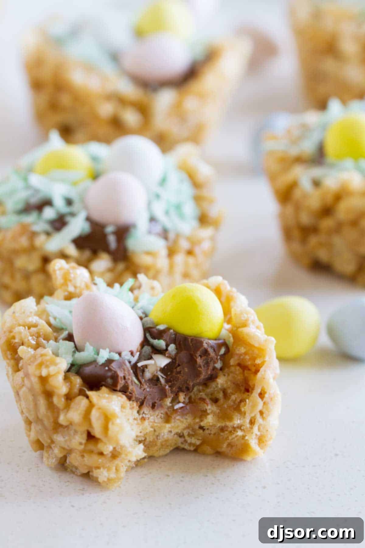 A close-up of an Easter Basket Scotcheroo with a small bite taken out, revealing the crispy peanut butter cereal base and the smooth chocolate and candy topping.