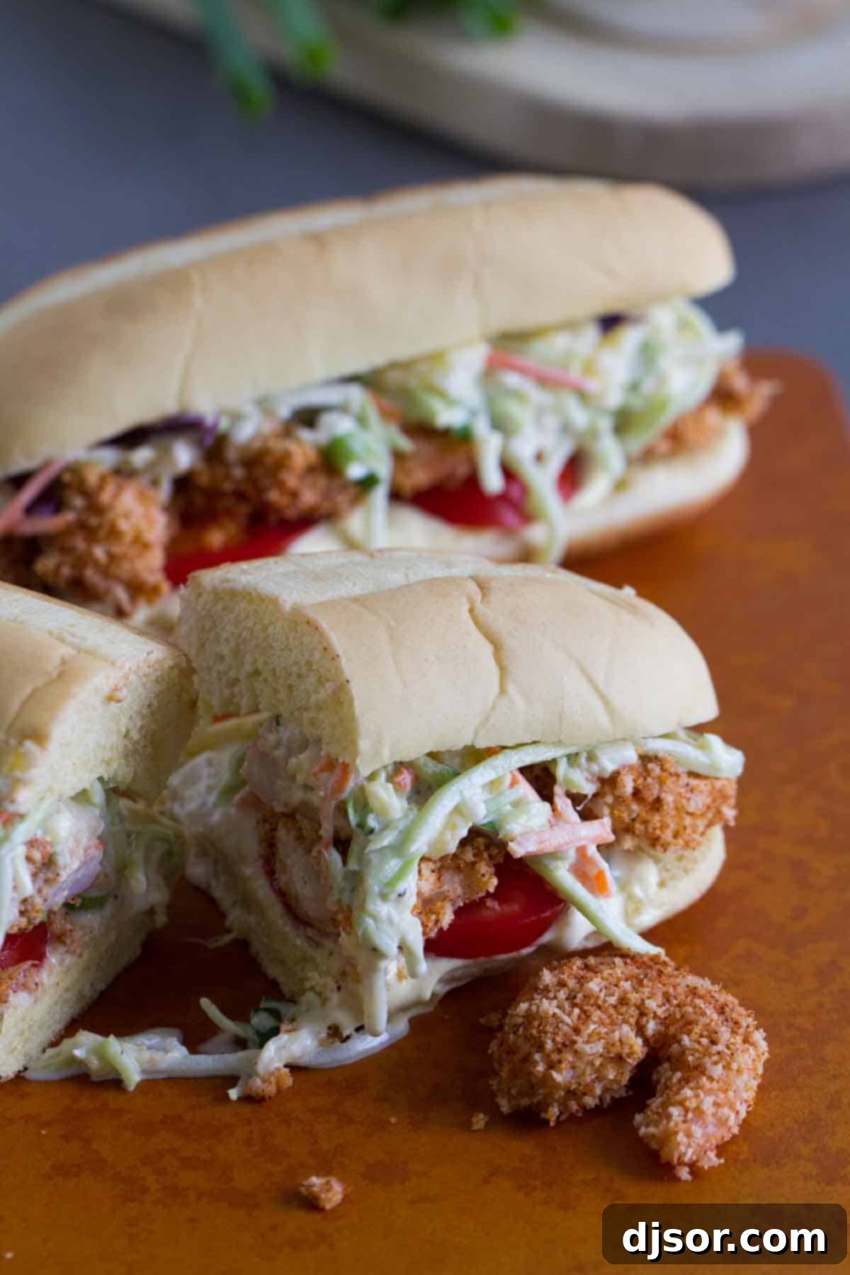 Shrimp Po Boy Sandwich with Pineapple Slaw cut in half, revealing layers of shrimp, slaw, and sauce.