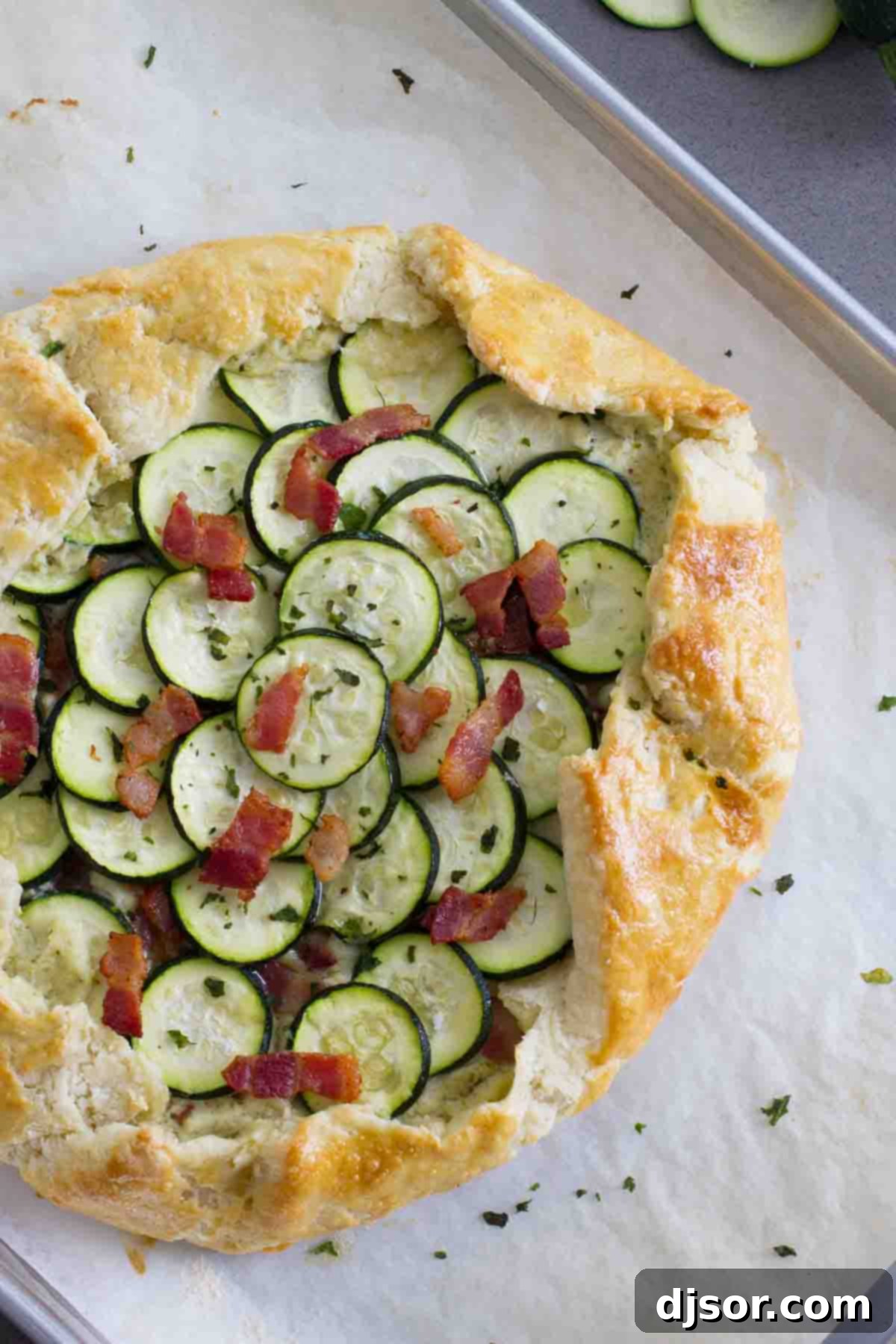 A tender, flaky crust is filled with a creamy ricotta filling, then topped with bacon and zucchini in this easy Zucchini Tart with Ricotta and Bacon that is perfect for a luncheon or a light dinner. Overhead view of a beautifully baked zucchini tart with ricotta and bacon, showcasing its golden crust and vibrant toppings.