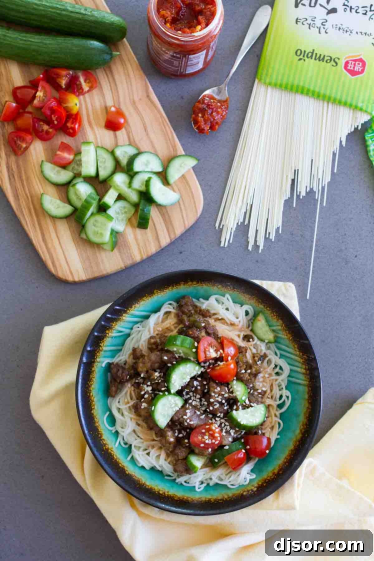 Close-up of a Spicy Pork Noodle Bowl featuring ground pork, fresh vegetables, and savory Chinese noodles.