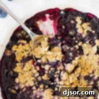Dish of blueberry crisp with serving spoon