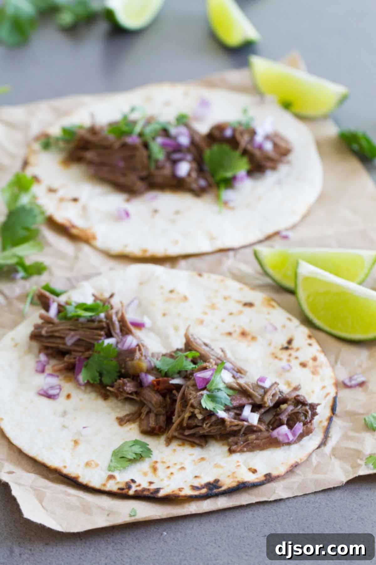 Spice up dinner in a fraction of the time with this Beef Barbacoa in the Instant Pot! Chipotle and cumin make this perfect for tacos, burritos, enchiladas and more! Tender beef barbacoa piled high on warm tortillas, garnished with fresh cilantro and red onion, ready for delicious tacos.