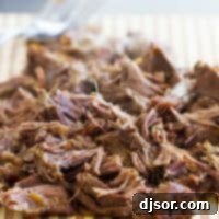 Instant Pot Beef Barbacoa 2 Shredded barbacoa beef on a cutting board, ready for various dishes.