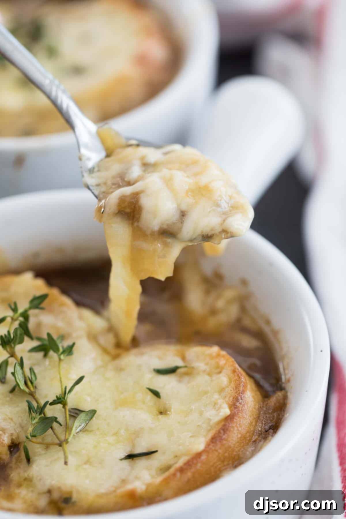 A spoon scooping up a hearty portion of French onion soup, showing the rich broth, tender onions, and melted cheese