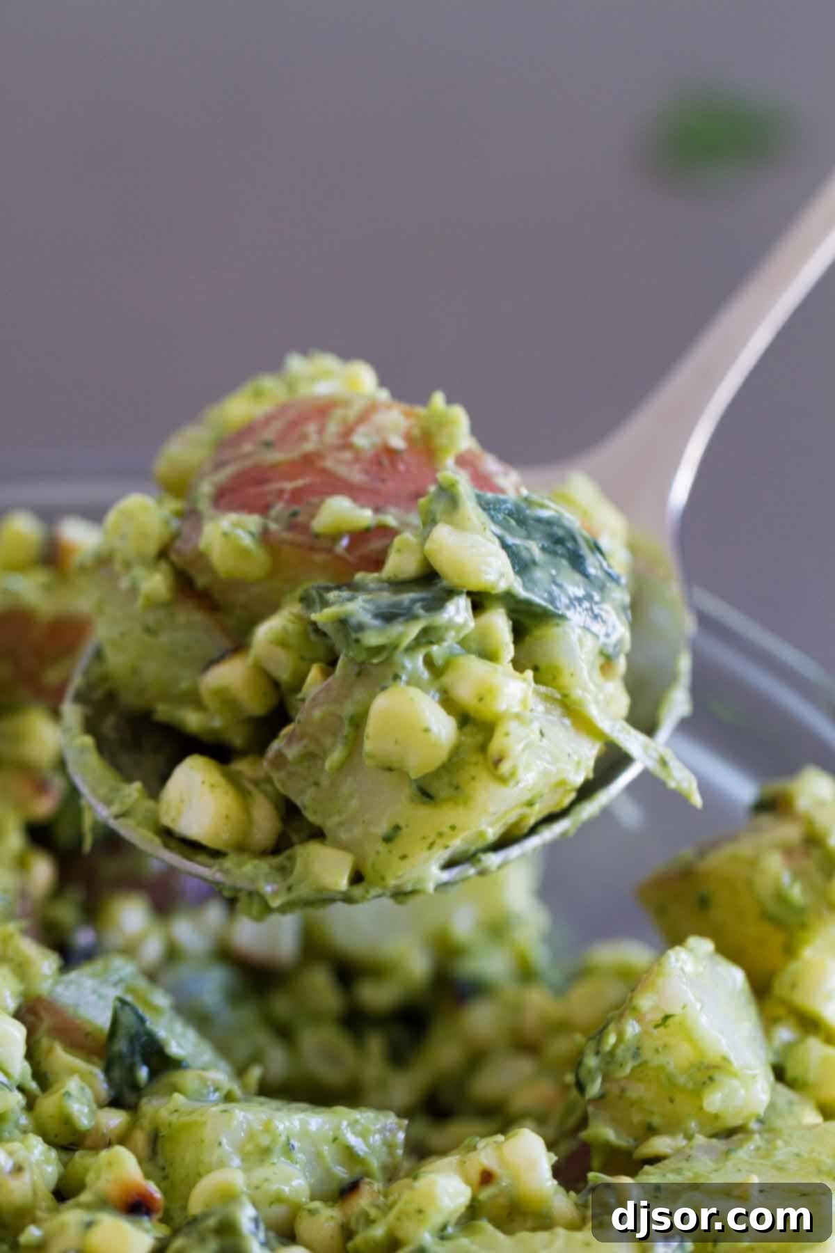 Potato salad with a Tex-Mex twist - this Potato Salad Recipe with Corn and Poblanos combines charred chiles and corn with potatoes and an avocado-cilantro dressing that’s irresistible. spoonful of Potato Salad with Corn and Poblanos