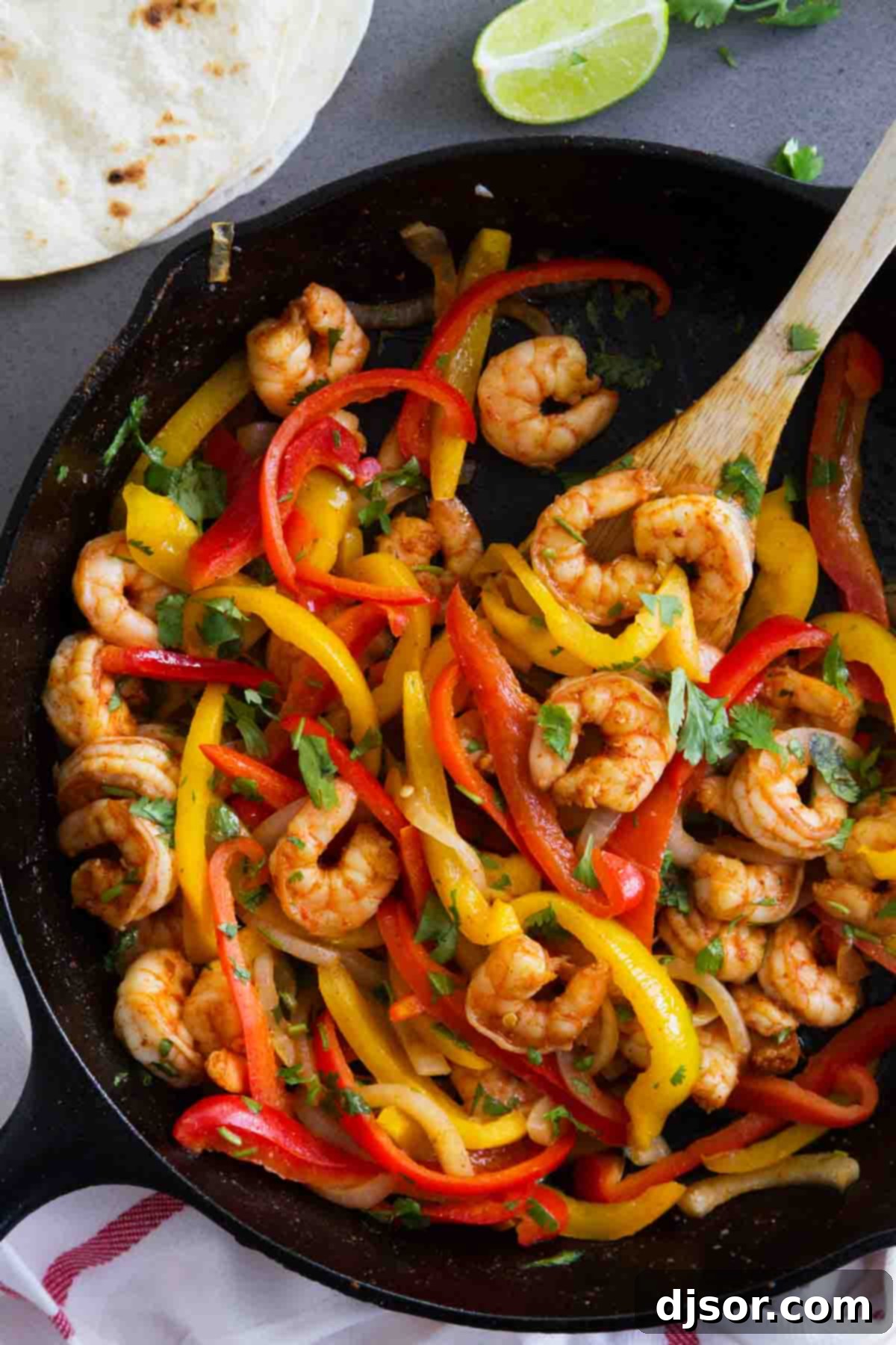Close-up of freshly cooked Shrimp Fajitas with bright red and yellow bell peppers, garnished with fresh cilantro.