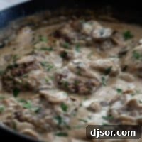 Homestyle Smothered Beef Steak 2 Salisbury Steak in a cast iron pan with gravy.