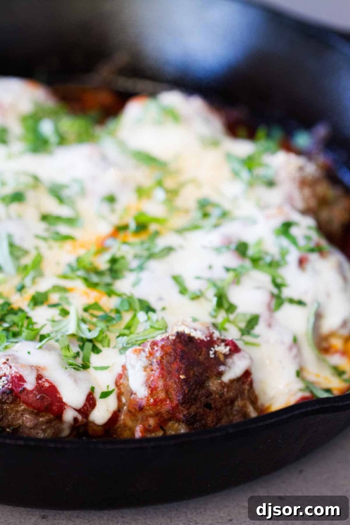 One-Pan Parmesan Meatball Dinner 4 Meatballs and sauce in a skillet topped with melted mozzarella cheese.
