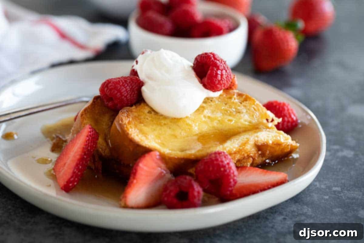 Creme Brulee French Toast: A delightful make-ahead breakfast casserole with a crispy caramel crust and creamy interior, perfect for any special occasion. plate with Creme Brulee French Toast topped with berries and whipped cream.