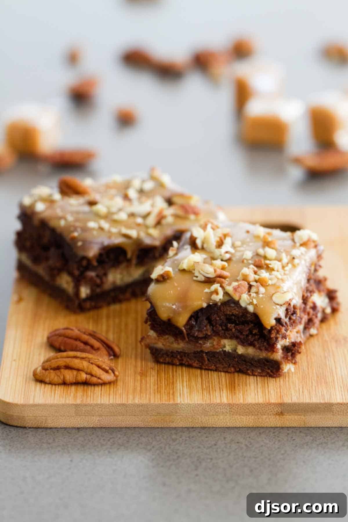 Two decadently layered Turtle Cheesecake Cookie Bars, showcasing the rich chocolate base, creamy caramel cheesecake, and generous toppings of chocolate, caramel, and pecans.